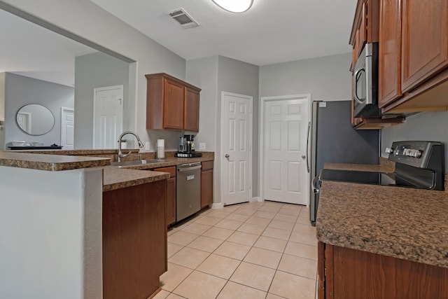 kitchen featuring stainless steel appliances, light tile patterned flooring, sink, and kitchen peninsula