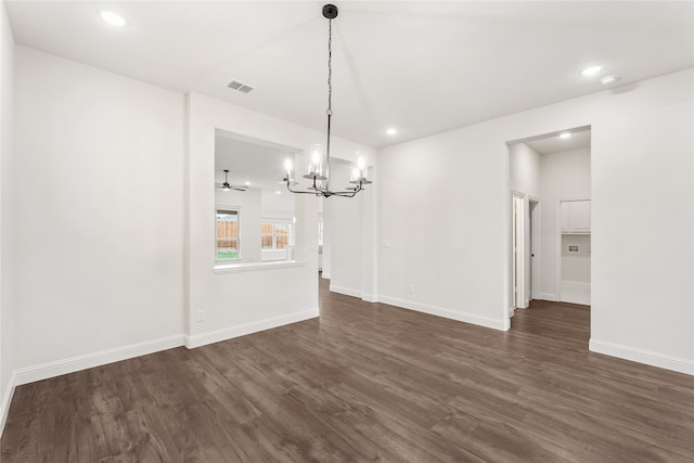 unfurnished dining area featuring ceiling fan with notable chandelier and dark hardwood / wood-style floors