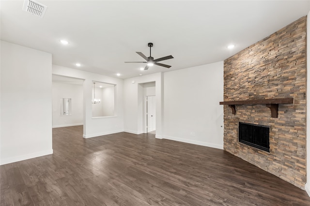 unfurnished living room featuring ceiling fan, a stone fireplace, and dark wood-type flooring