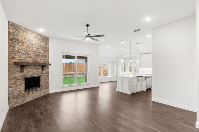 unfurnished living room with ceiling fan, a fireplace, dark wood-type flooring, and sink