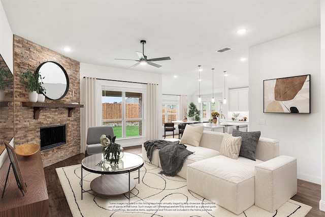 living room with sink, ceiling fan, dark hardwood / wood-style floors, and a stone fireplace