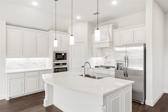 kitchen featuring decorative light fixtures, a kitchen island with sink, appliances with stainless steel finishes, and white cabinetry