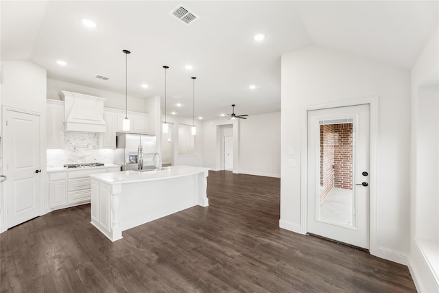 kitchen featuring custom exhaust hood, lofted ceiling, a kitchen island with sink, appliances with stainless steel finishes, and dark hardwood / wood-style floors