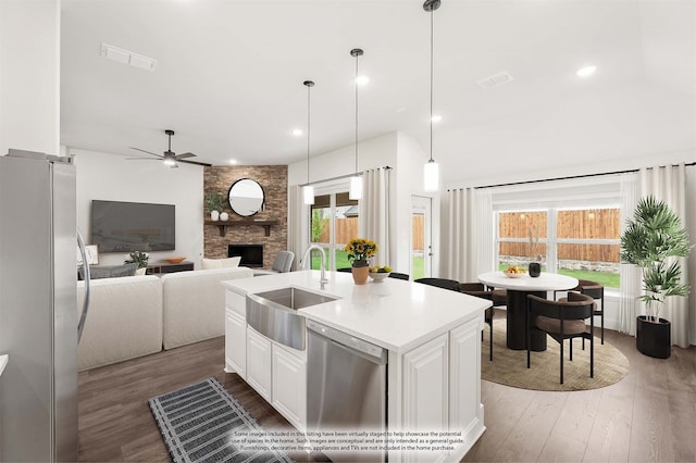 kitchen with dark wood-type flooring, sink, an island with sink, white cabinets, and stainless steel appliances