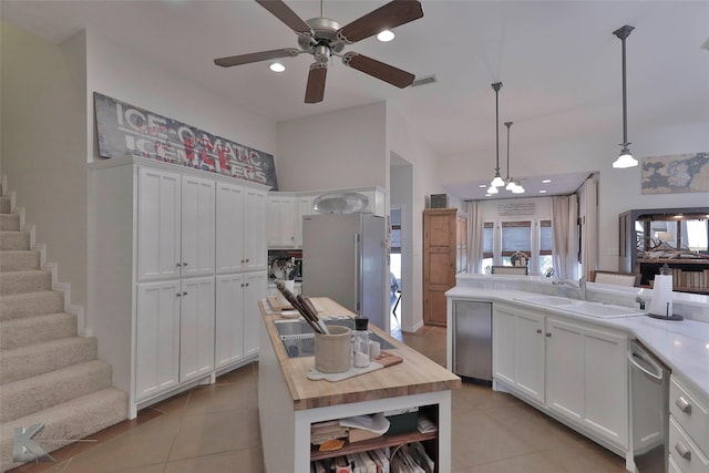 kitchen featuring wood counters, sink, pendant lighting, white cabinets, and light tile patterned flooring