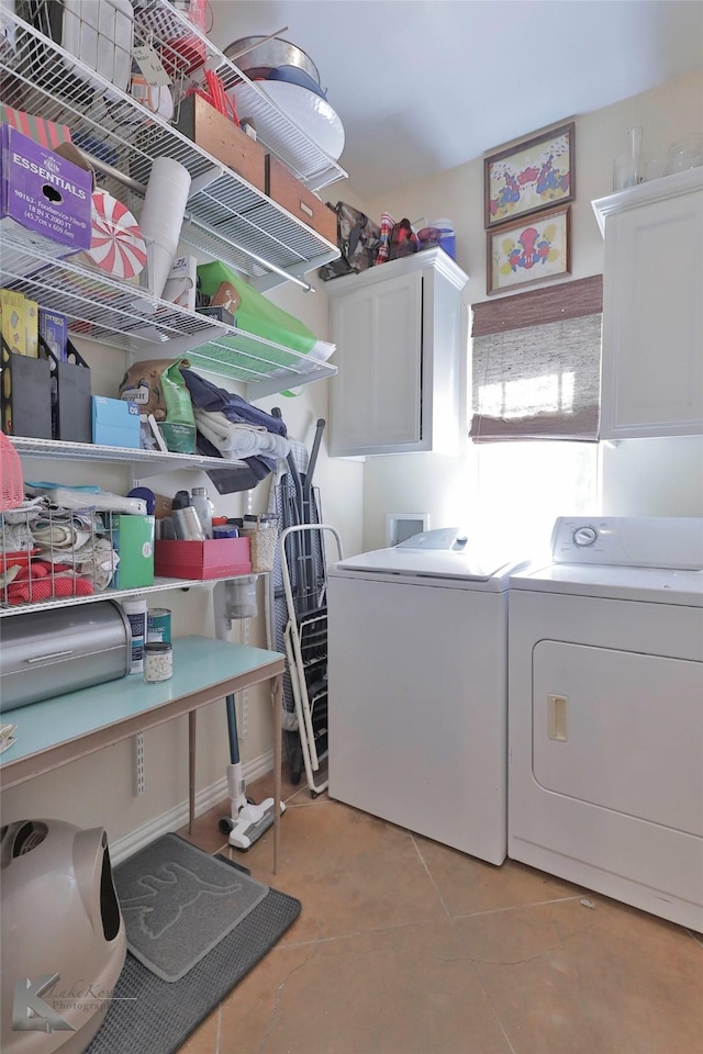 clothes washing area featuring washer and dryer, light tile patterned floors, and cabinets