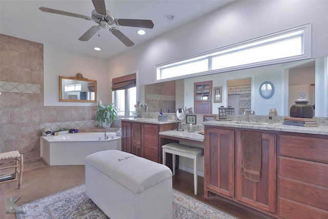 bathroom featuring a bath, vanity, tile walls, and ceiling fan