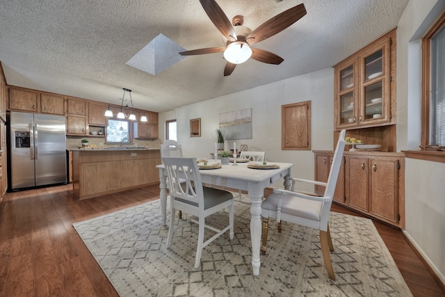 dining space with hardwood / wood-style floors, ceiling fan, a textured ceiling, and a skylight