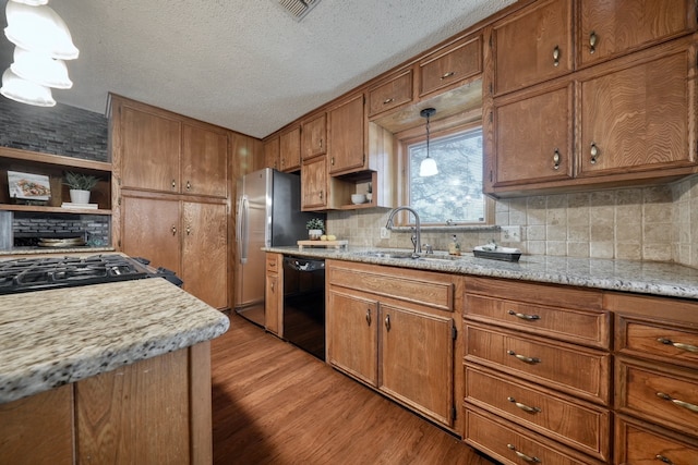 kitchen with black dishwasher, a textured ceiling, light hardwood / wood-style flooring, sink, and decorative light fixtures