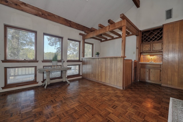 interior space featuring beam ceiling, dark parquet flooring, and wood walls