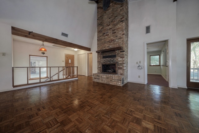 unfurnished living room with dark parquet floors, high vaulted ceiling, and a brick fireplace