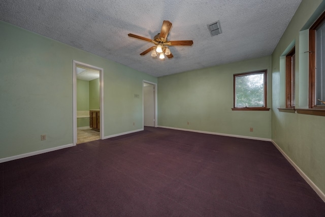 spare room with a textured ceiling, dark carpet, and ceiling fan