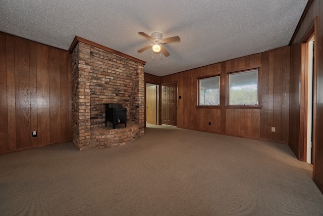 unfurnished living room with a wood stove, a textured ceiling, wood walls, and ceiling fan