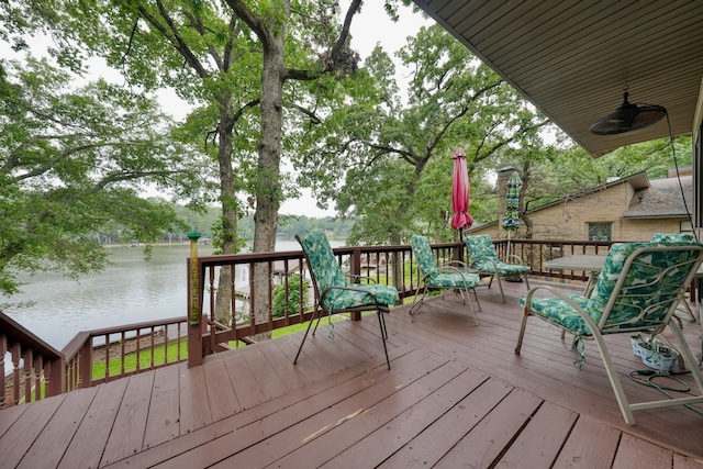 wooden terrace with a water view and ceiling fan