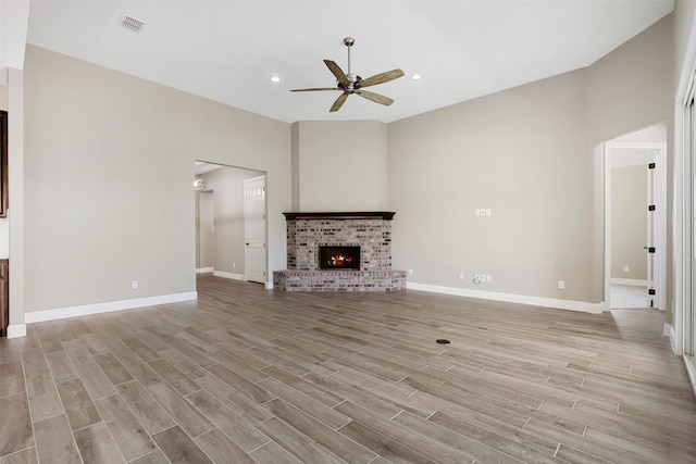 unfurnished living room with a brick fireplace, light hardwood / wood-style flooring, and ceiling fan