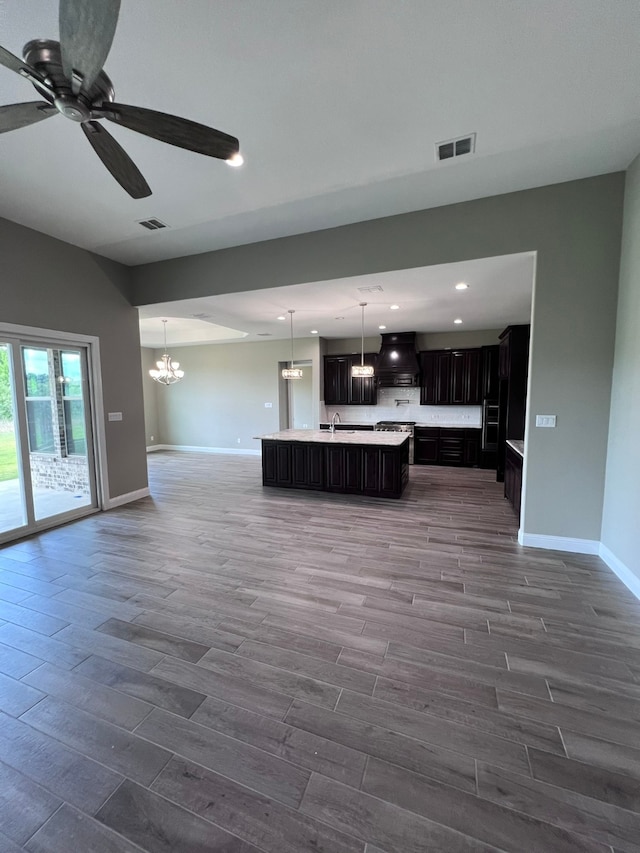 unfurnished living room featuring ceiling fan with notable chandelier, hardwood / wood-style floors, and sink