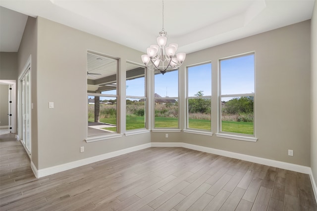 spare room featuring a wealth of natural light, a notable chandelier, and light hardwood / wood-style floors