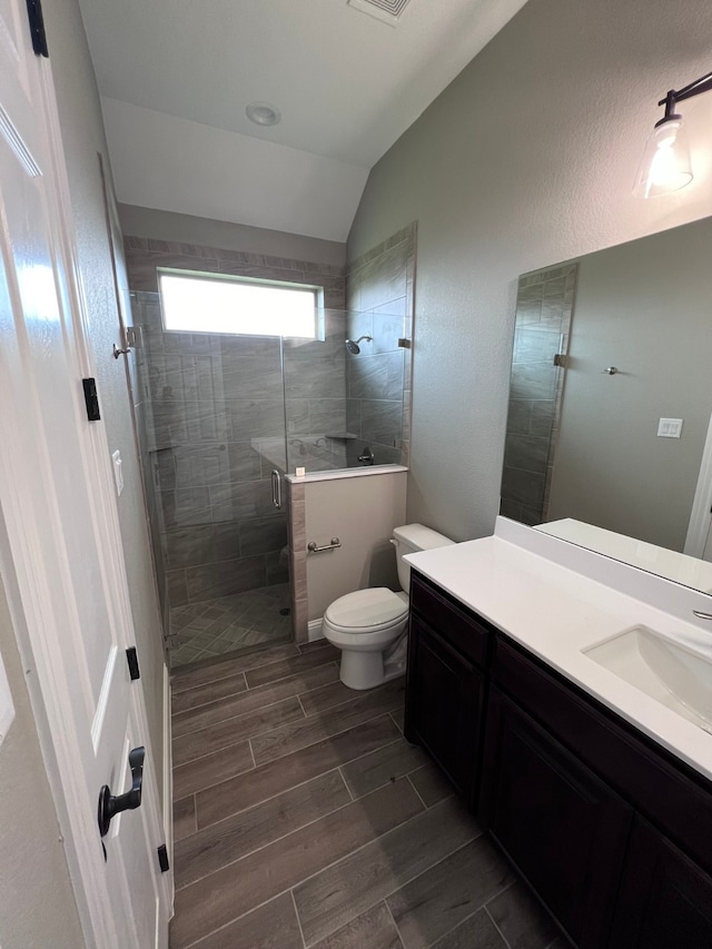 bathroom featuring vanity, toilet, lofted ceiling, and an enclosed shower