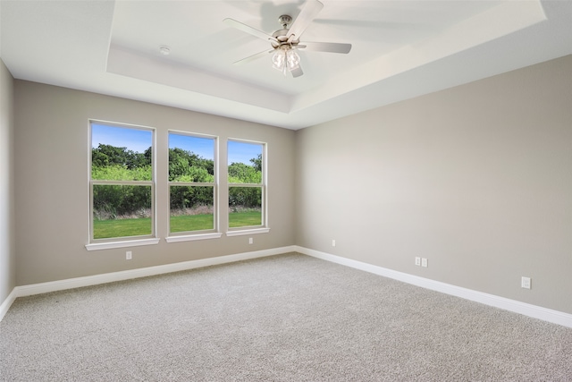 carpeted spare room featuring ceiling fan and a tray ceiling