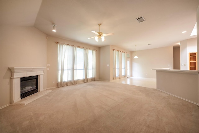 unfurnished living room with a tile fireplace, light carpet, vaulted ceiling, and ceiling fan