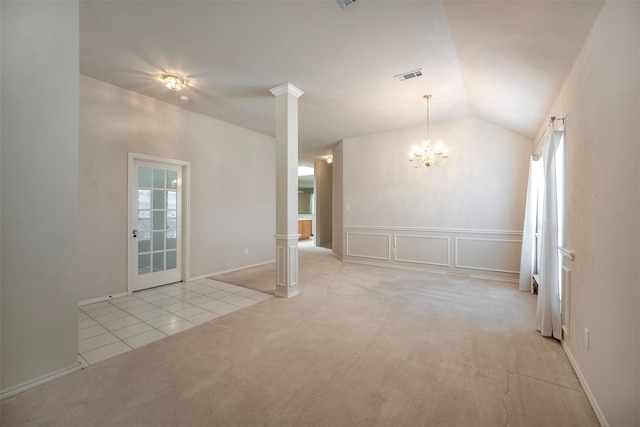 spare room with a chandelier, light colored carpet, decorative columns, and vaulted ceiling