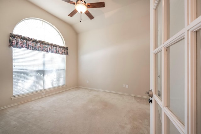 carpeted empty room featuring ceiling fan, lofted ceiling, and a wealth of natural light