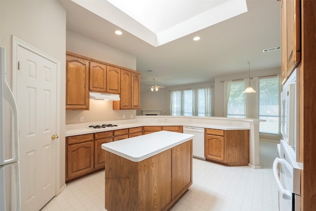 kitchen featuring ceiling fan, a center island, hanging light fixtures, kitchen peninsula, and white appliances