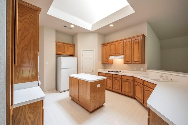 kitchen featuring a kitchen island, white appliances, sink, and a skylight