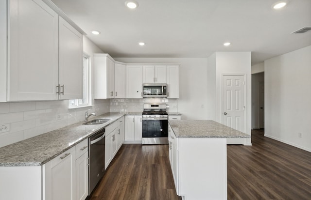 kitchen featuring white cabinets, a center island, stainless steel appliances, and dark wood-type flooring