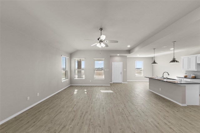 unfurnished living room with ceiling fan, lofted ceiling, light hardwood / wood-style floors, and sink