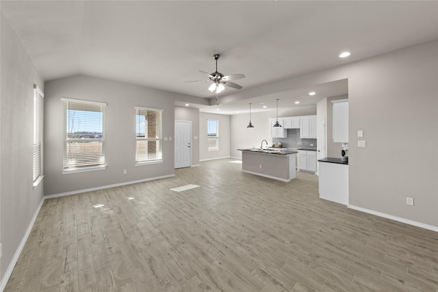 unfurnished living room with vaulted ceiling, ceiling fan, and light hardwood / wood-style flooring