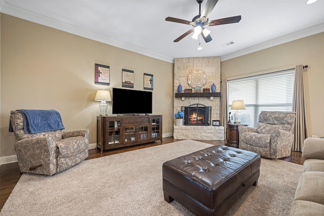 living room with hardwood / wood-style floors, ceiling fan, a stone fireplace, and ornamental molding