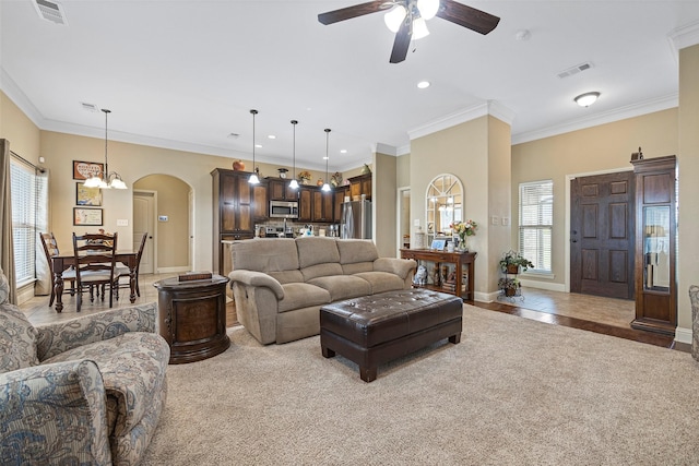 living room featuring crown molding, light carpet, and ceiling fan with notable chandelier