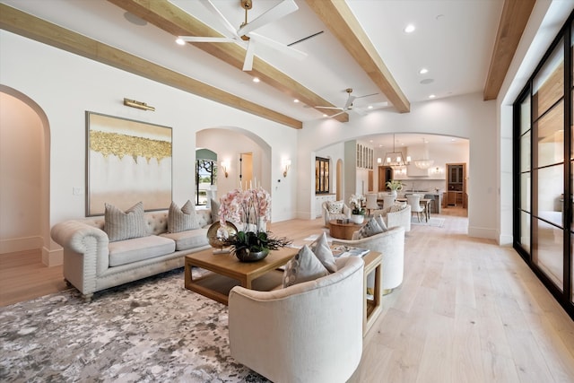 living room featuring beam ceiling, ceiling fan with notable chandelier, and light wood-type flooring