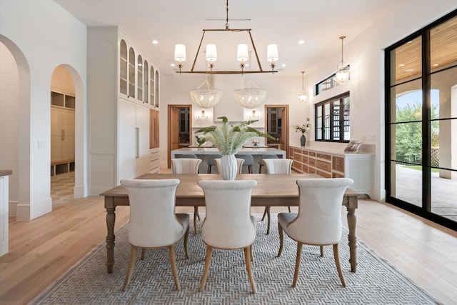 dining space with a high ceiling, light hardwood / wood-style flooring, and a notable chandelier