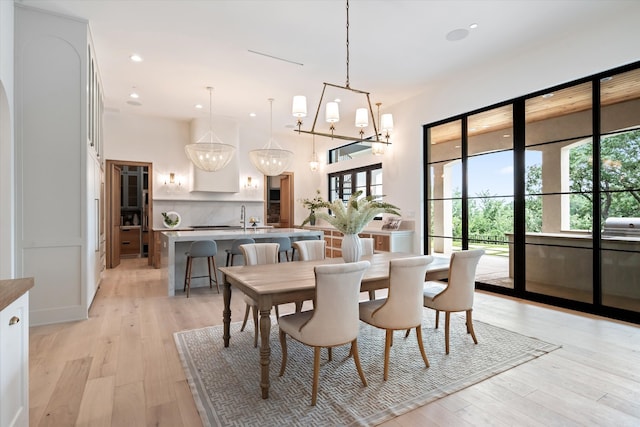 dining area with a chandelier, sink, and light wood-type flooring