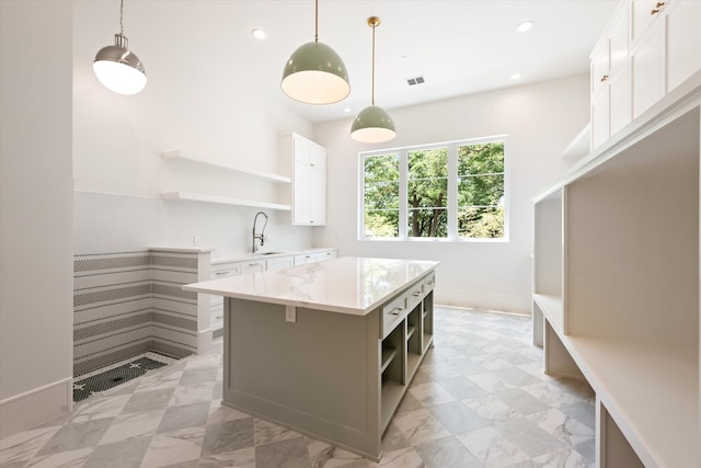 kitchen featuring white cabinetry, light tile patterned floors, a kitchen island, hanging light fixtures, and sink