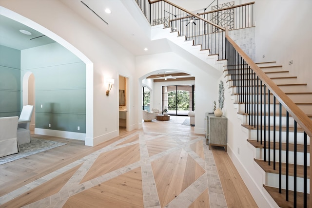 foyer with ceiling fan, light wood-type flooring, and a high ceiling