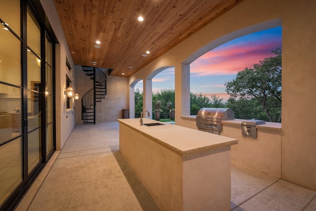 patio terrace at dusk featuring sink and area for grilling