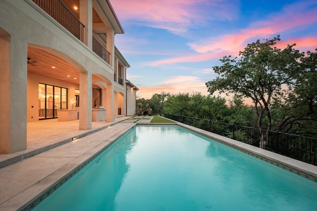 pool at dusk featuring a patio