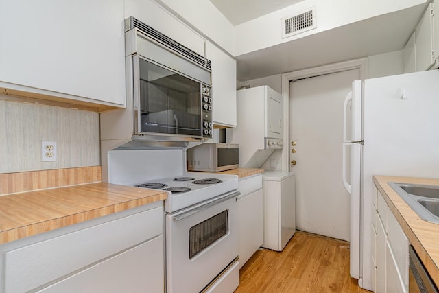 kitchen with white cabinets, white appliances, and light hardwood / wood-style floors