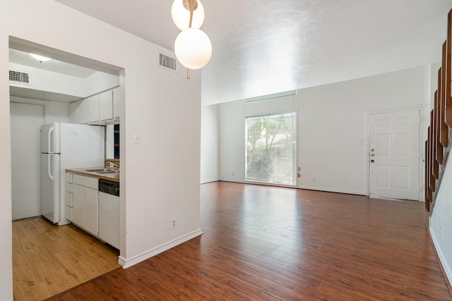 kitchen with white fridge, hardwood / wood-style flooring, dishwasher, white cabinets, and sink