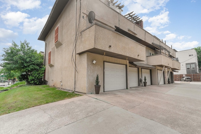 view of side of property featuring a lawn, a balcony, and a garage