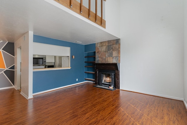 unfurnished living room with hardwood / wood-style flooring and a tile fireplace