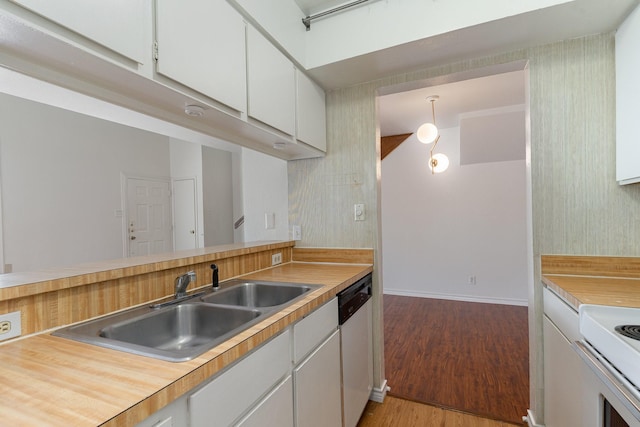 kitchen featuring white cabinets, sink, hanging light fixtures, hardwood / wood-style flooring, and stainless steel dishwasher