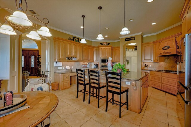 kitchen with a center island, tasteful backsplash, dark stone counters, light tile patterned flooring, and ornamental molding