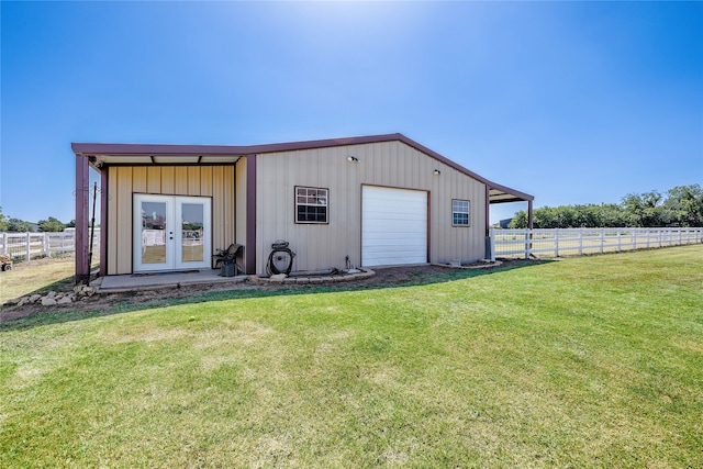 view of outbuilding featuring a rural view, a garage, a yard, and french doors