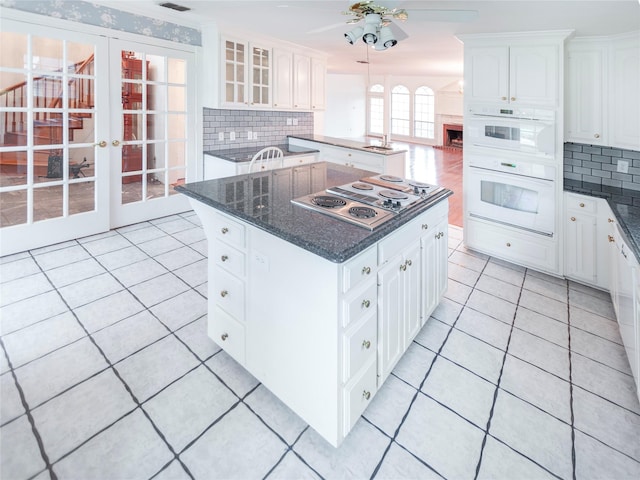 kitchen with a kitchen island, white cabinetry, and white double oven