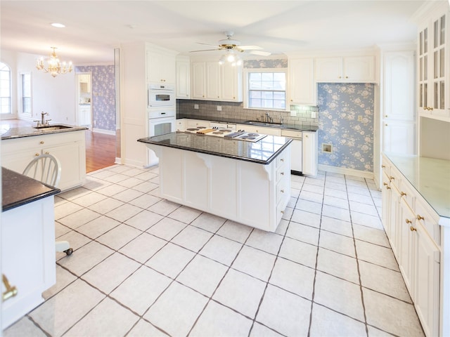 kitchen with sink, a center island, a kitchen breakfast bar, and white cabinetry