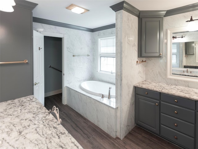 bathroom with vanity, hardwood / wood-style flooring, ornamental molding, and tiled bath